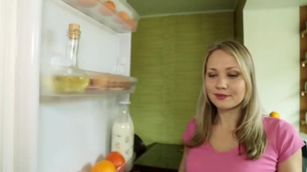 Женщина открывает холодильник и достает курицу . — стоковое видео