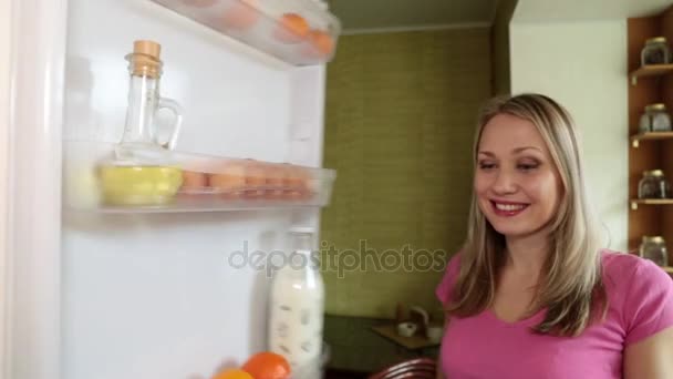 Žena v kuchyni vytáhne ovoce z lednice. — Stock video
