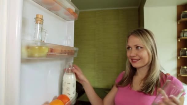 A woman takes milk out of the refrigerator and pours it into a glass. — Stock Video