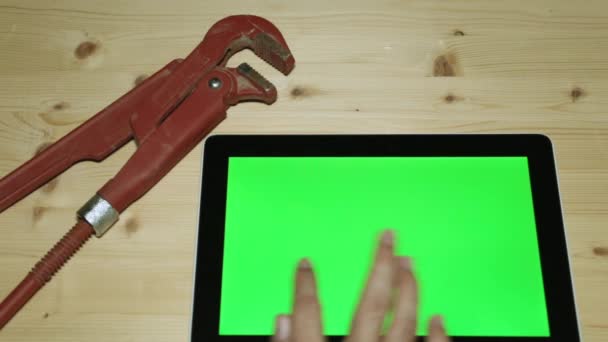 Llave de fontanería y tableta con una pantalla verde para su contenido . — Vídeos de Stock