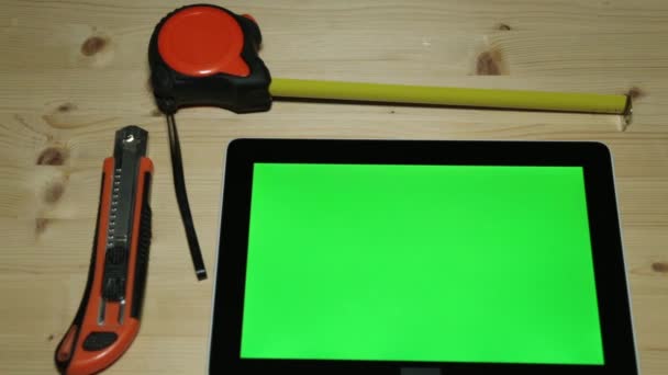 Stavební nůž, střihač, stavební měřicí páska a tabletový počítač s zelený displej. — Stock video