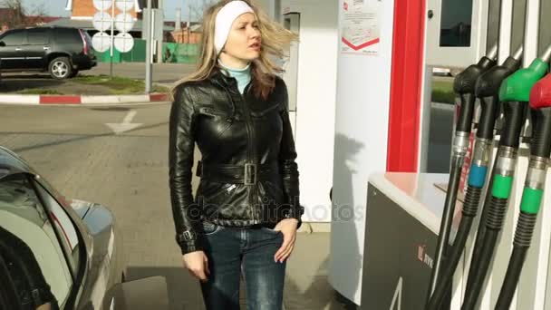 Una donna alla stazione di servizio. L'uomo versa benzina costosa in macchina . — Video Stock