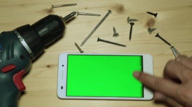 Elektrikli tornavida ve yeşil bir ekran ile smartphone.