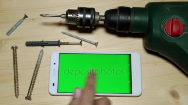 Elektro matkap ve yeşil bir ekran ile smartphone.