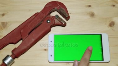 Bir akıllı telefon ile yeşil bir ekran ve bir sıhhi tesisat anahtar.