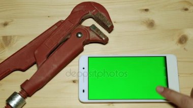 Yeşil bir ekran ve bir sıhhi tesisat aracı ile bir akıllı telefon.