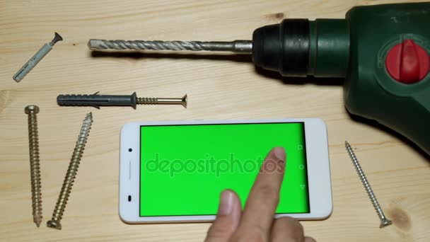 Bouw perforatie en smartphone met een groen scherm. — Stockvideo