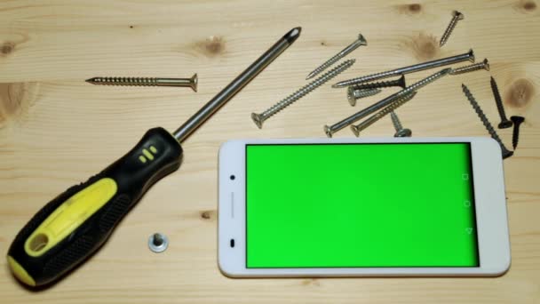 Screwdriver, screws and smartphone with a green display. — Stock Video