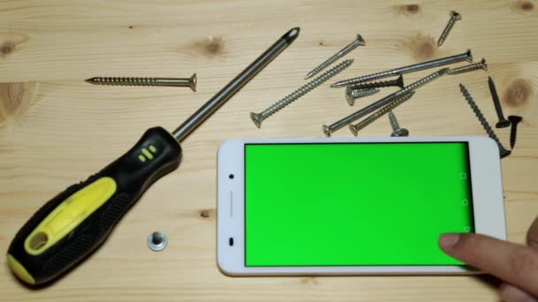 Destornillador de mano, tornillos y smartphone con pantalla verde para tu contenido . — Vídeo de stock