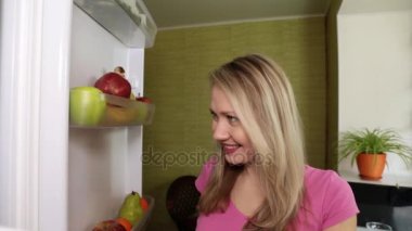 kadın buzdolabı açar ve armut yiyor.