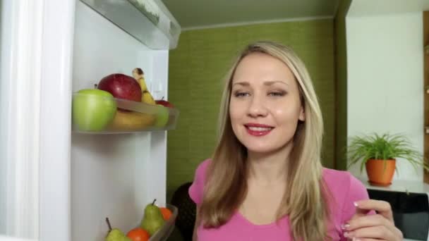 Una mujer está comiendo una manzana verde en la cocina . — Vídeos de Stock