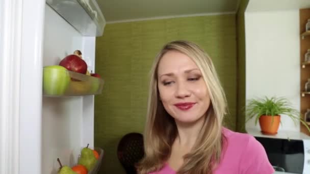 Seorang wanita sedang makan apel merah di dapur . — Stok Video