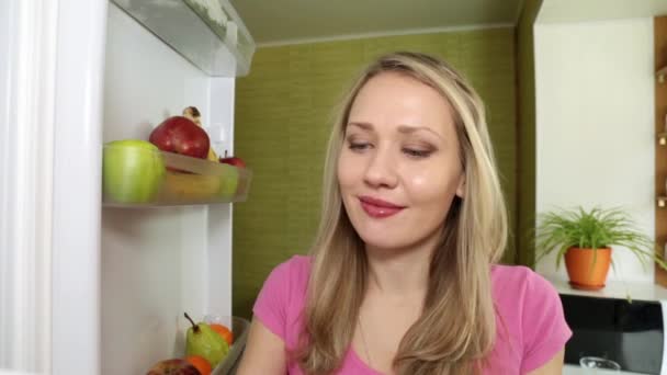 Uma mulher está comendo uma pêra verde em casa na cozinha . — Vídeo de Stock