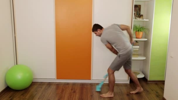 Un homme joyeux lave le sol avec une serpillière et danse . — Video