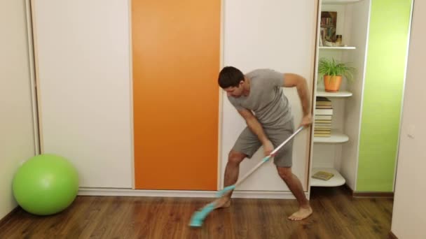 Un uomo positivo canta e pulisce il pavimento con uno straccio . — Video Stock
