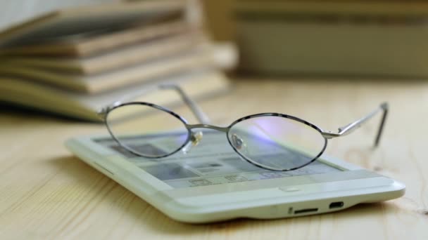 Libro electrónico y gafas en el fondo de los libros de papel . — Vídeo de stock