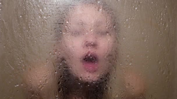Woman touches her lips to the glass in the shower — Stockvideo