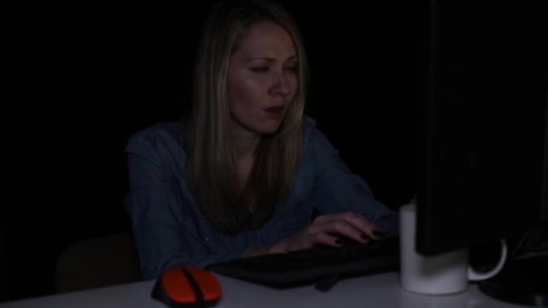 Tired woman works at the computer in the dark. — Stock Video