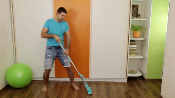 Egy ember hallgat zenét, táncot, és tisztítja a padlót. — Stock videók