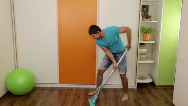 Een man danst, zingt en wast de vloer in het huis. — Stockvideo