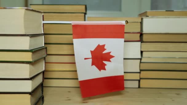 Bandera de Canadá y libros en papel. Bandera de Canadá en el fondo de los libros . — Vídeos de Stock