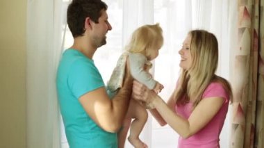 Pencerenin yanında bir çocukla mutlu genç aile.