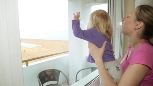 Ibu dan anak yang bahagia melihat ke luar jendela . — Stok Video