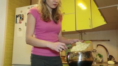 Genç bir kadın mutfakta yemek pişiriyor. Ev rutin.