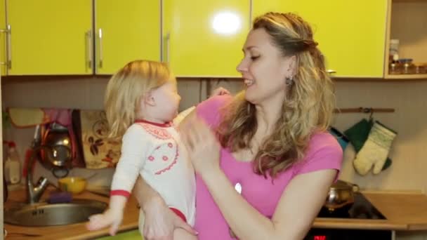 Una mujer con un niño pequeño en la cocina. Mamá y su hija en casa . — Vídeos de Stock