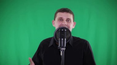 Yeşil bir arka plan üzerinde bir mikrofona bir adam şarkı söylüyor.