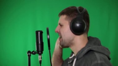 Adam şarkı söylüyor ve mikrofona rap okur. Rapçi, şarkıcı yeşil bir arka plan üzerinde.