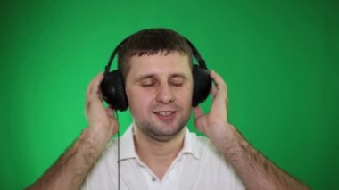 Kulaklıklar bir erkekte yeşil bir arka plan üzerinde müzik dinler.