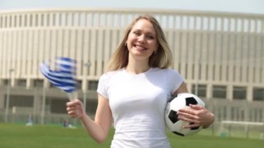 Yunanistan bayrağı ile futbol fanatiği. Kadın bir Yunan bayrağı ve bir futbol topu.