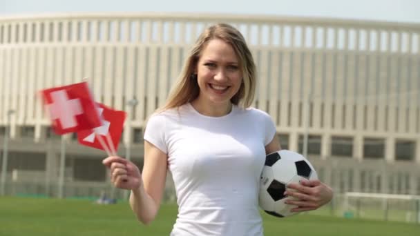Fotbollsfan med flaggan i Schweiz. Kvinna med en schweizisk flagga och en fotboll. — Stockvideo