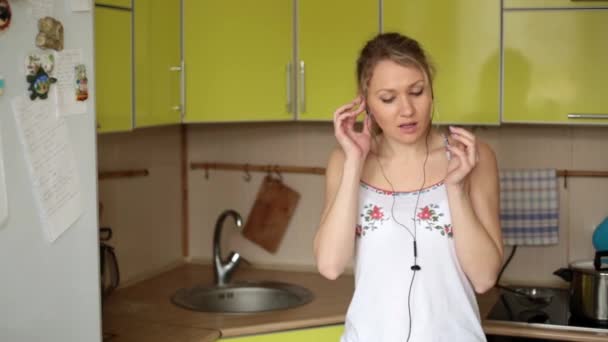 Mladá žena poslouchá hudbu a tance v kuchyni. — Stock video