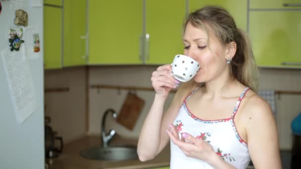 A nő iszik teát vagy kávét a konyhában reggel. — Stock videók