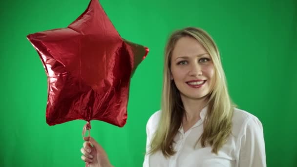 Woman with a red balloon in the shape of a star on a green background. — Stock Video