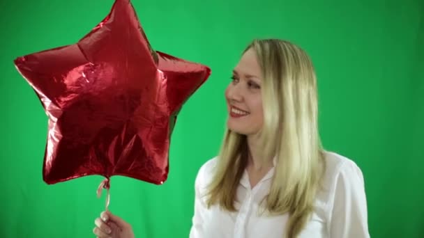 Junge Frau mit rotem Luftballon auf grünem Hintergrund. — Stockvideo