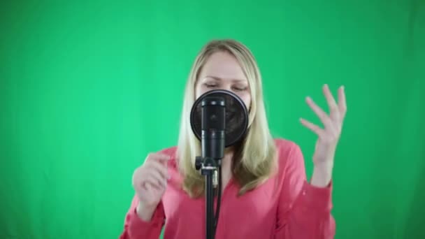 Une femme chante dans un micro sur fond vert . — Video