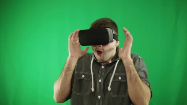 Un hombre con gafas de realidad virtual sobre un fondo verde . — Vídeos de Stock