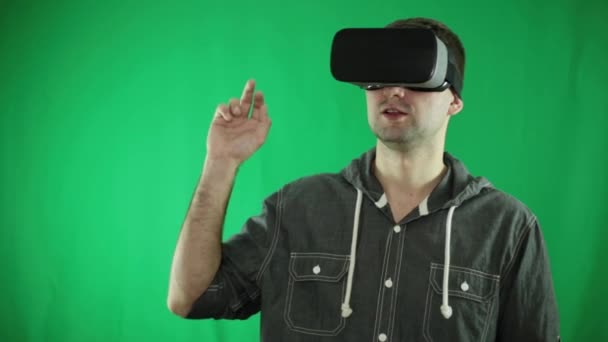 Un joven con gafas de realidad virtual hace gestos con la mano en el aire . — Vídeos de Stock