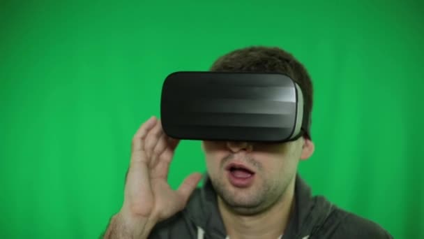 Um homem com óculos de realidade virtual, de perto. óculos VR, fundo verde . — Vídeo de Stock