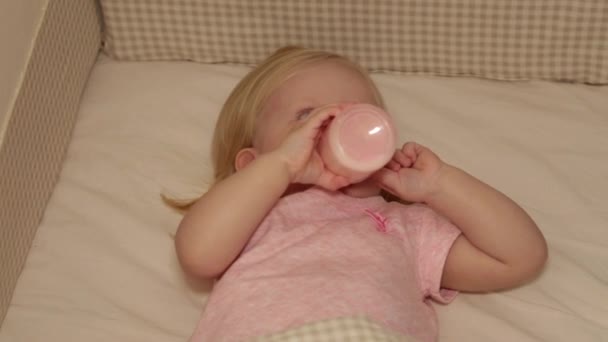 Děťátko jí z láhve na dětském lůžku. Dítě usíná v postýlce. — Stock video