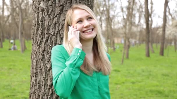 Mujer joven hablando por teléfono en la naturaleza . — Vídeos de Stock