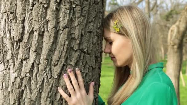 Een jonge vrouw raakt een boom. Rust, rust, eenheid met de natuur en harmonie. — Stockvideo