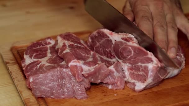 Un hombre está cortando carne en la cocina . — Vídeos de Stock