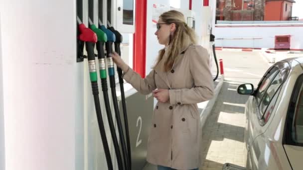 Junge Frau an Tankstelle schüttet Benzin in Auto. — Stockvideo