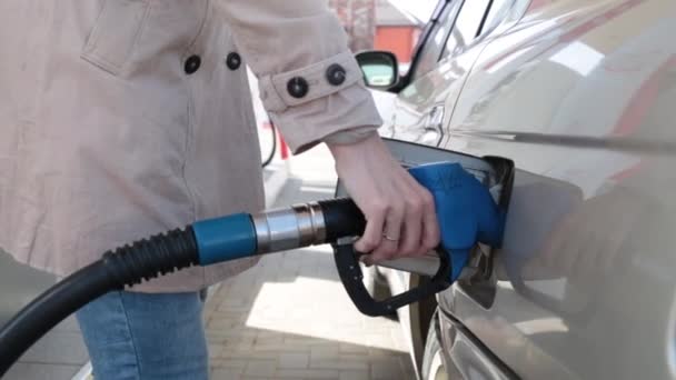 Una gasolinera, una mano de mujer sostiene una pistola de gasolina . — Vídeo de stock