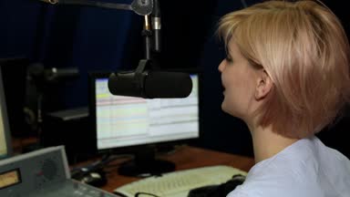 Bir kadın Dj bir radyo istasyonu bir stüdyoda bir mikrofona konuşur