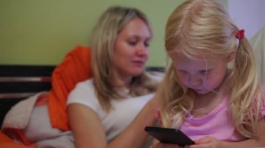 Modern bir aile akıllı telefon kullanır. Telefonları olan kızı olan bir anne..